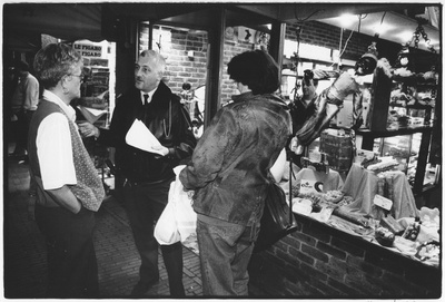 351281 Afbeelding van een buurtonderzoek door de politie in winkels na een overval op een bakkerswinkel in de ...